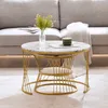A nesting set of round coffee tables with marble-look tops and gold metal frames, placed in a living room setting next to a sofa. Náhľad obrázku produktu