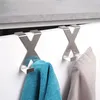 Two metal 'X' shaped hooks hanging over a white cabinet door, with towels draped on them. Anteprima dell’immagine prodotto