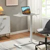 A white adjustable laptop table with a laptop, cup, and saucer on it, placed next to a marble cabinet and a grey office chair in a room with a window. Náhľad obrázku produktu