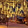 A snowy street decorated with icicle-shaped lights hanging from trees and buildings. Produktbild-Vorschau