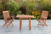 A wooden garden furniture set consisting of a table and two chairs, set on a paved patio with a garden in the background. Náhled obrázku produktu