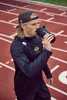 A man drinking from a shaker bottle on a running track. Produktbild-Vorschau