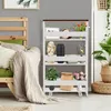 A white four-tier rolling storage cart with various items on its shelves, placed next to a wooden bed frame and a large potted plant. Náhľad obrázku produktu