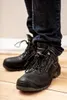 A person wearing dark blue jeans and black work boots. Náhled obrázku produktu