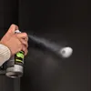 A hand holding a spray can spraying a substance onto a dark surface. Produktbild-Vorschau