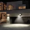 A modern house at night with a garage door open and lights illuminating the driveway. Produktbild-Vorschau