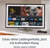 A smart display device showing a streaming interface with movie posters and app icons, placed on a countertop with a remote control nearby. Podgląd zdjęcia produktu