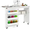A white sewing table with a sewing machine on top and various spools of thread stored in shelves on the side. Anteprima dell’immagine prodotto