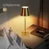 A bedside table with a gold lamp, a book, and a phone. Anteprima dell’immagine prodotto