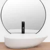 A white oval basin sink with a black faucet in front of a large round mirror. Anteprima dell’immagine prodotto