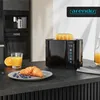 A black Arendo toaster with a slice of bread on top, placed on a kitchen counter next to a glass of orange juice, a croissant on a plate with blueberries, and a coffee machine in the background. Produktbild-Vorschau