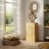 A decorative pedestal with a sculpture and mirror in a room with macrame curtains and pillows. Voir les images du produit