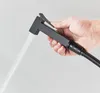 A hand holding a black bidet sprayer with water spraying from it. Náhľad obrázku produktu