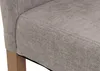 A close-up view of the corner of a light gray upholstered chair, showing the texture of the fabric and a portion of a natural-colored wooden leg. Podgląd zdjęcia produktu