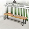 A wooden bench with a hat and magazine on it, placed on a patio in front of a white railing and green grass. Produktbild-Vorschau