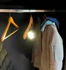 A closet interior with clothes hanging on hangers and a small LED light. Produktbild-Vorschau
