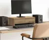 A computer monitor stand with drawers, a keyboard, and speakers on a desk. Náhľad obrázku produktu