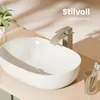 A modern bathroom sink with a faucet and toothbrushes, set against a soft, neutral background with dappled light. Anteprima dell’immagine prodotto