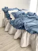 A bed with blue bedding and a light gray bed skirt. Podgląd zdjęcia produktu