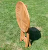 A round wooden folding table is set up on a grassy lawn. Produktbild-Vorschau