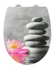 A toilet seat cover with a zen-like design featuring a stacked stone cairn and a pink water lily reflected in water. Produktbild-Vorschau