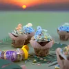 Cupcakes decorated with dinosaur figures and sprinkles, set against a sunset background. Anteprima dell’immagine prodotto
