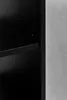 A close-up view of a black shelf on a black bookcase, with a gray wall in the background. Náhľad obrázku produktu