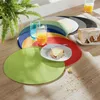 A table setting with colorful placemats, glasses of juice, and a slice of cake. Produktbild-Vorschau