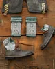 A flat lay of traditional Bavarian clothing items, including lederhosen, knitted leg warmers, and boots, arranged on a wooden surface. Produktbild-Vorschau