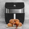 An air fryer with a plate of cinnamon sugar donut holes in front of it. Produktbild-Vorschau