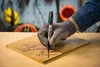 A gloved hand is marking a piece of wood with a black Sharpie marker. Anteprima dell’immagine prodotto