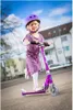 A young girl riding a purple scooter outdoors. Produktbild-Vorschau