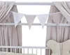 A close-up view of a baby crib with draped fabric and a string of triangular flags. Produktbild-Vorschau