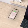 A pink Magsafe power bank is charging a phone on a wooden desk, with a keyboard visible on the right. Náhled obrázku produktu
