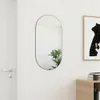 A mirror hanging on a white wall next to a door and a framed picture. Produktbild-Vorschau