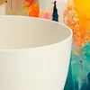 A close-up view of a white planter with a colorful abstract painting in the background. Voir les images du produit