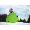 A person in ski gear holding a green sled on a snowy slope. Anteprima dell’immagine prodotto