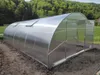 A greenhouse in an outdoor setting with trees and grass in the background. Produktbild-Vorschau