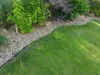 A garden bed with a black plastic edging separating the grass from the gravel and plants. Anteprima dell’immagine prodotto