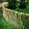 A curved wooden picket fence in a garden setting with green grass and trees in the background. Produktbild-Vorschau