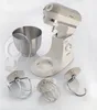 A collection of stand mixer accessories and the mixer itself, laid out on a white surface. Náhled obrázku produktu