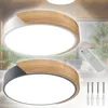 Two modern LED ceiling lights with wood accents are displayed, one white and one gray, with a remote control and mounting hardware shown. Voir les images du produit