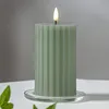 A green LED candle with a flickering flame sits on a clear glass coaster on a white surface, with a light gray background. Podgląd zdjęcia produktu