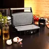 A kitchen counter with a grill, oil bottle, and garlic. Voir les images du produit