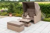 A wicker outdoor sofa with a canopy, a coffee table, and an ottoman on a paved patio with a garden in the background. Produktbild-Vorschau