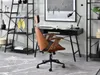 A modern office chair in front of a desk with a bookshelf in the background. Produktbild-Vorschau