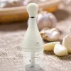 A white electric garlic chopper is placed on a textured brown surface, with several cloves of garlic scattered around it. Náhľad obrázku produktu
