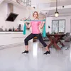 A woman is doing exercises with a resistance band in a modern kitchen. Produktbild-Vorschau