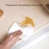 A hand is shown wiping up a spill on a beige shelf liner with a paper towel. Produktbild-Vorschau
