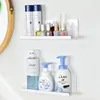 Two white shelves mounted on a white wall, displaying various toiletries and cosmetic products. Voir les images du produit